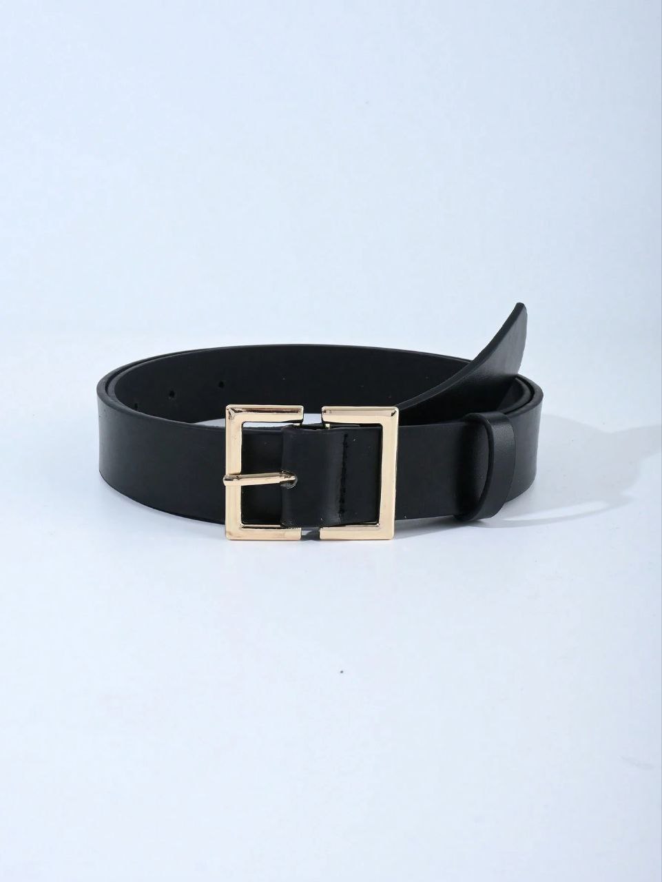 Black belt with a gold buckle on a light gray background