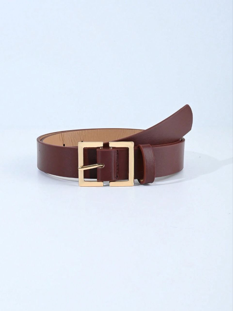 Brown leather belt with a gold buckle on a light blue background