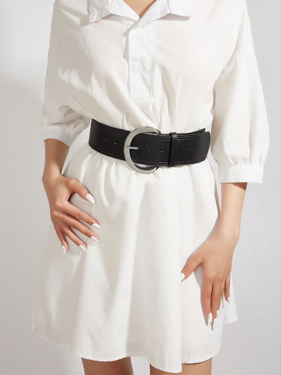 White dress with a black belt on a plain background