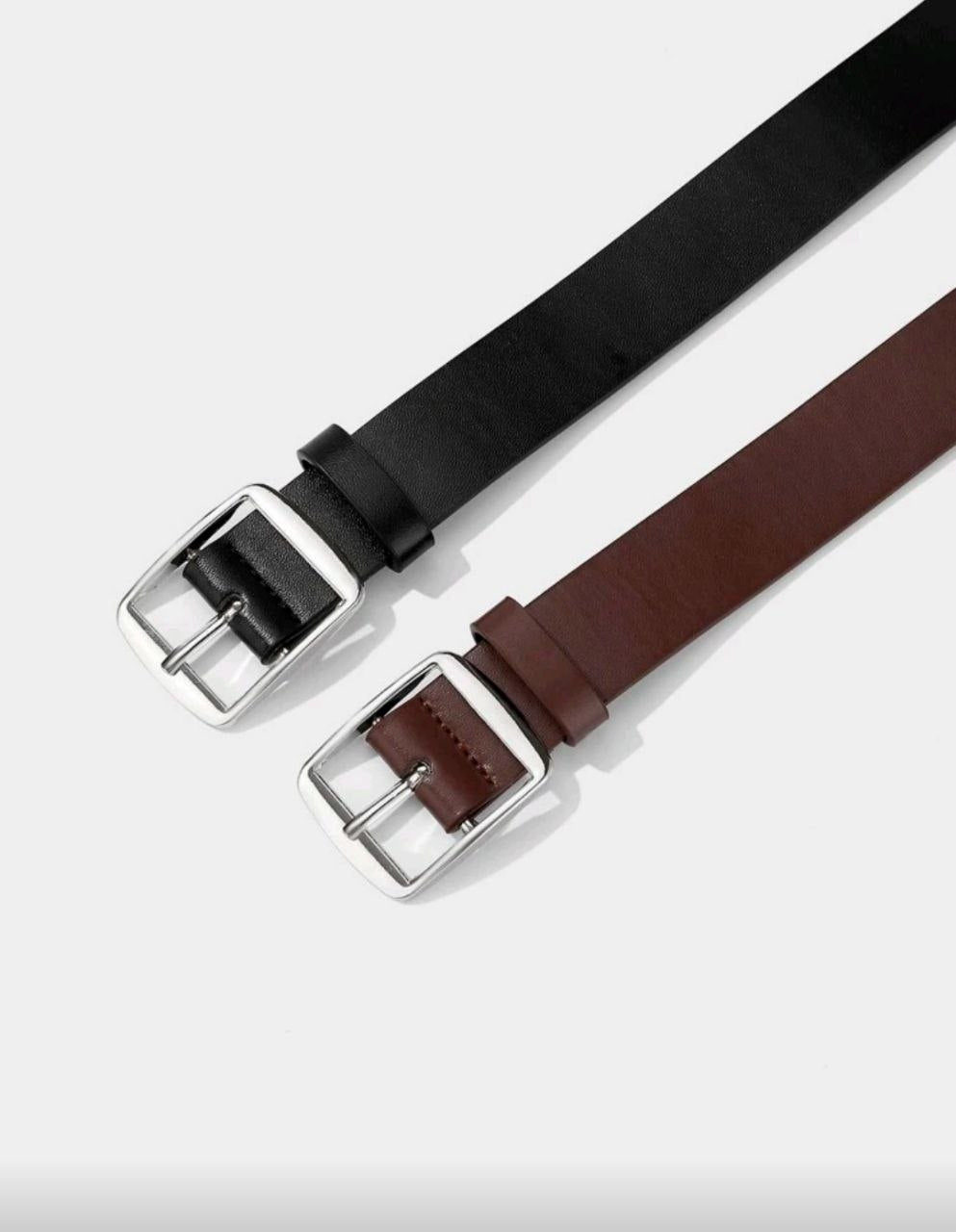 Two belts, one black and one brown, with silver buckles on a light gray background.
