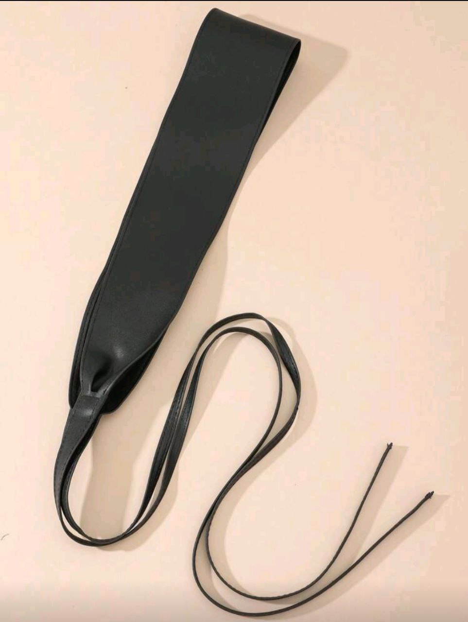 Black leather strap on a beige background