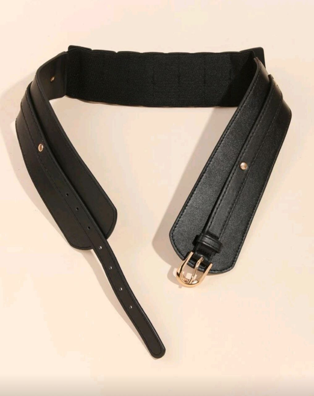 Black leather belt with gold buckle on a beige background