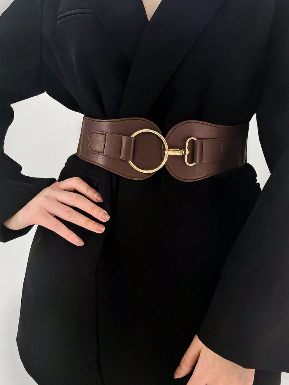 Person wearing a black outfit with a wide brown belt featuring a gold buckle on a white background
