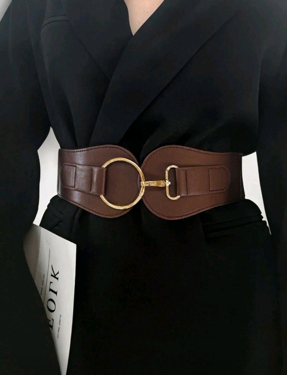 Brown belt with gold buckle worn by a person in a black outfit.