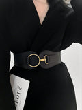 Person wearing a black outfit with a wide belt featuring a gold buckle on a white background