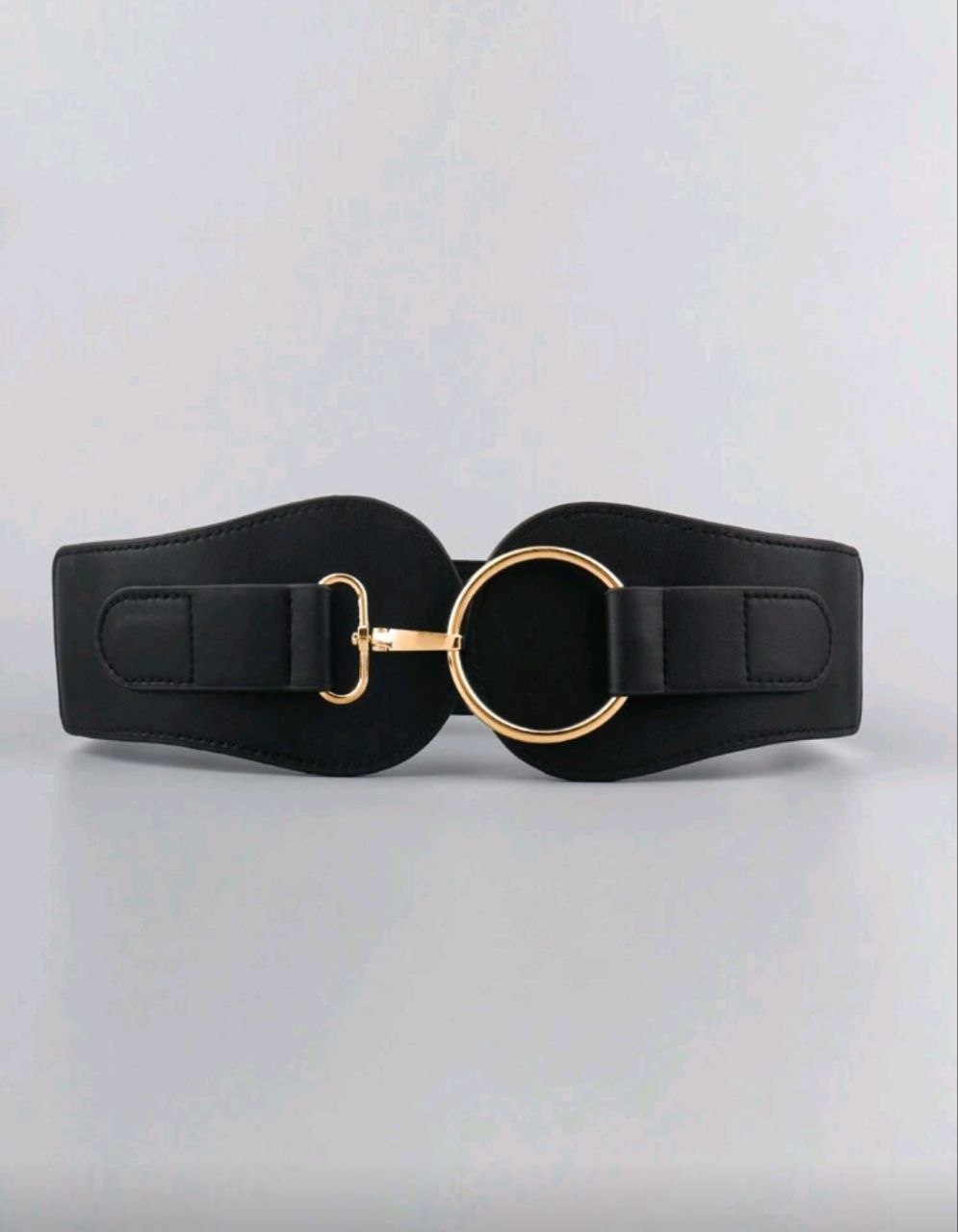 Black belt with a gold buckle on a light gray background