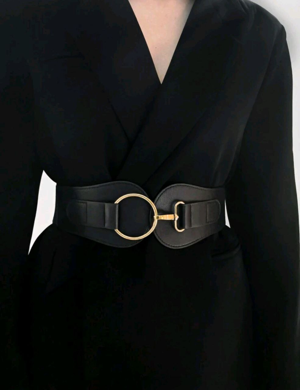 Black coat with a gold belt buckle on a plain background