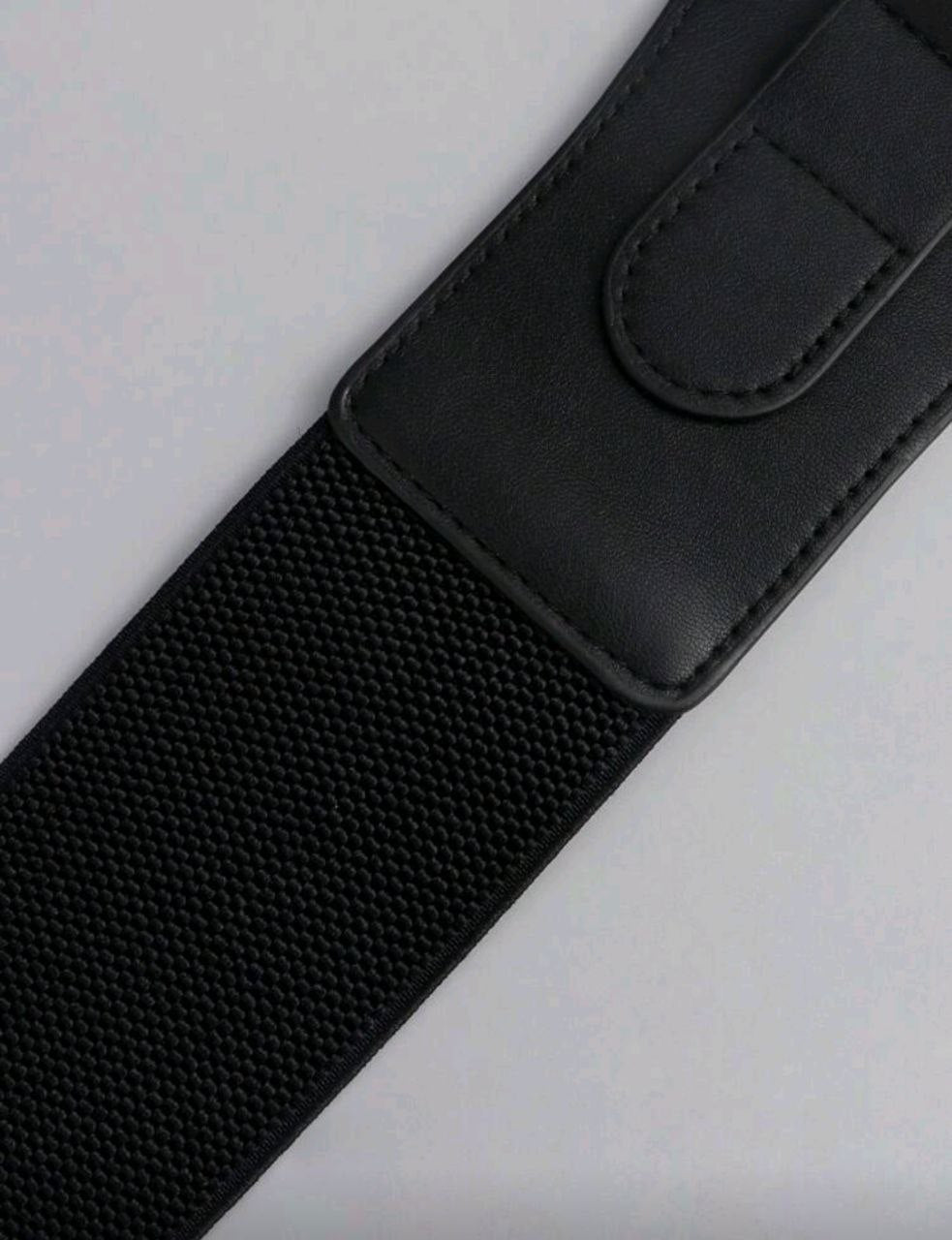 Black belt with a textured strap on a light gray background