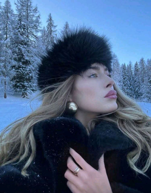 Woman in a fur hat and coat standing in a snowy forest