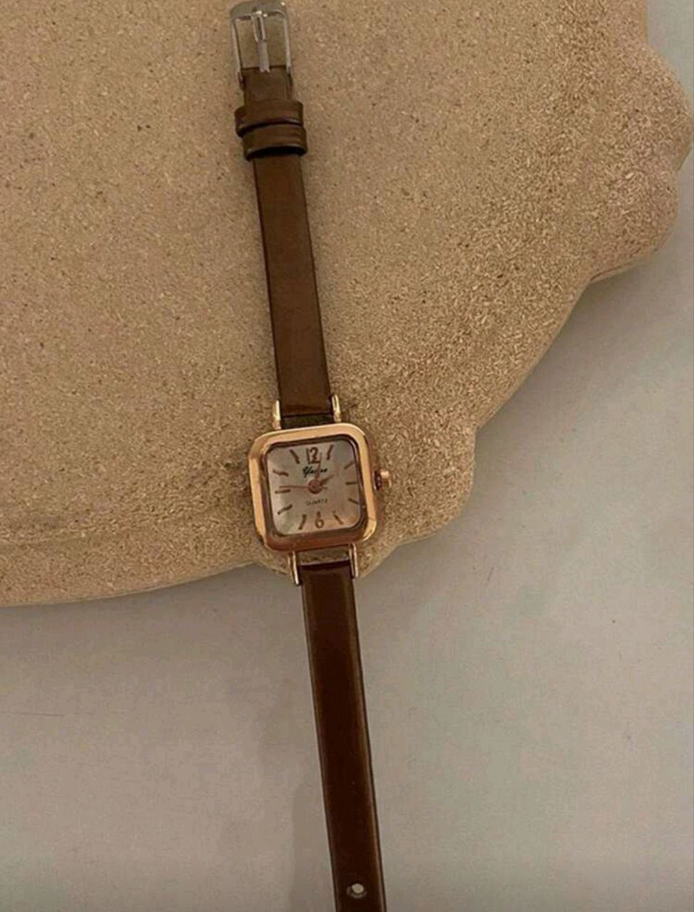 Vintage-style watch with brown leather strap on a textured surface