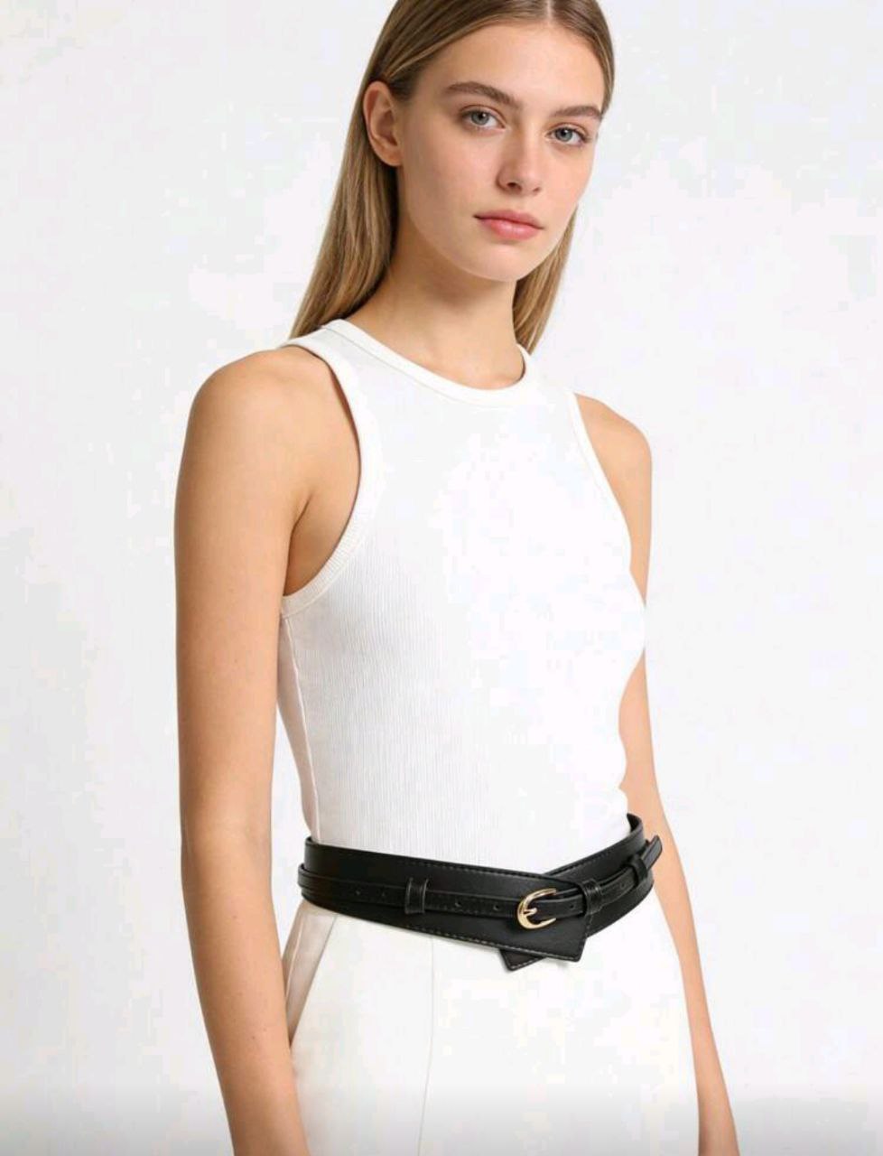 Woman wearing a white sleeveless top with a black belt on a white background